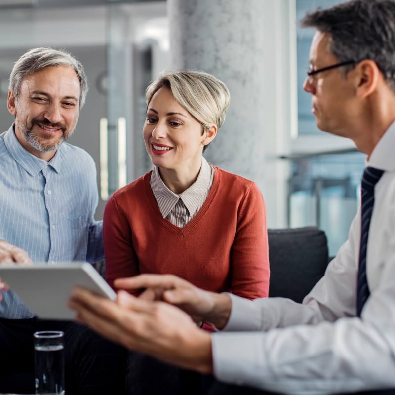 happy-mid-adult-couple-using-touchpad-with-their-financial-consultant-in-the-office-.jpg